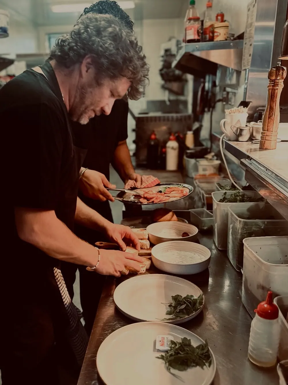 A chef plating dishes along the pass in The Little Larder kitchen